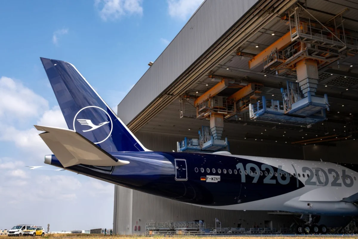 Lufthansas first A350 1000 arrives in anniversary livery Lufthansa aircraft tail with logo near a large maintenance hangar and overhead equipment