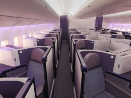 Premium airline cabin with individual lie flat pods in a 2 2 2 layout and purple accents