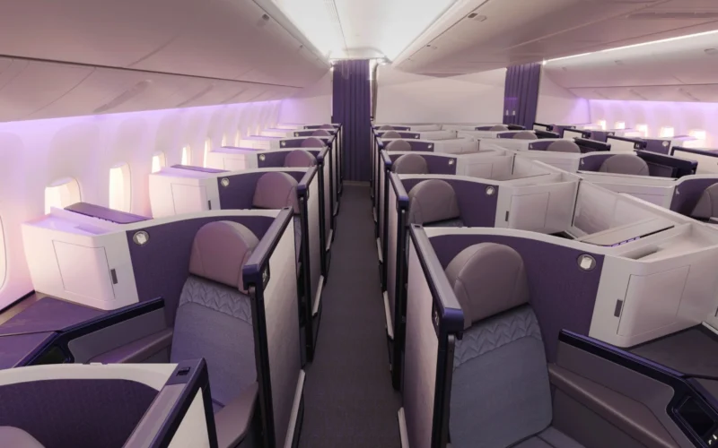 Premium airline cabin with individual lie flat pods in a 2 2 2 layout and purple accents