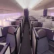 Premium airline cabin with individual lie flat pods in a 2 2 2 layout and purple accents