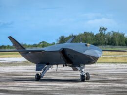 Stealth drone aircraft on a runway gray delta wing body with tail fins and landing gear visible