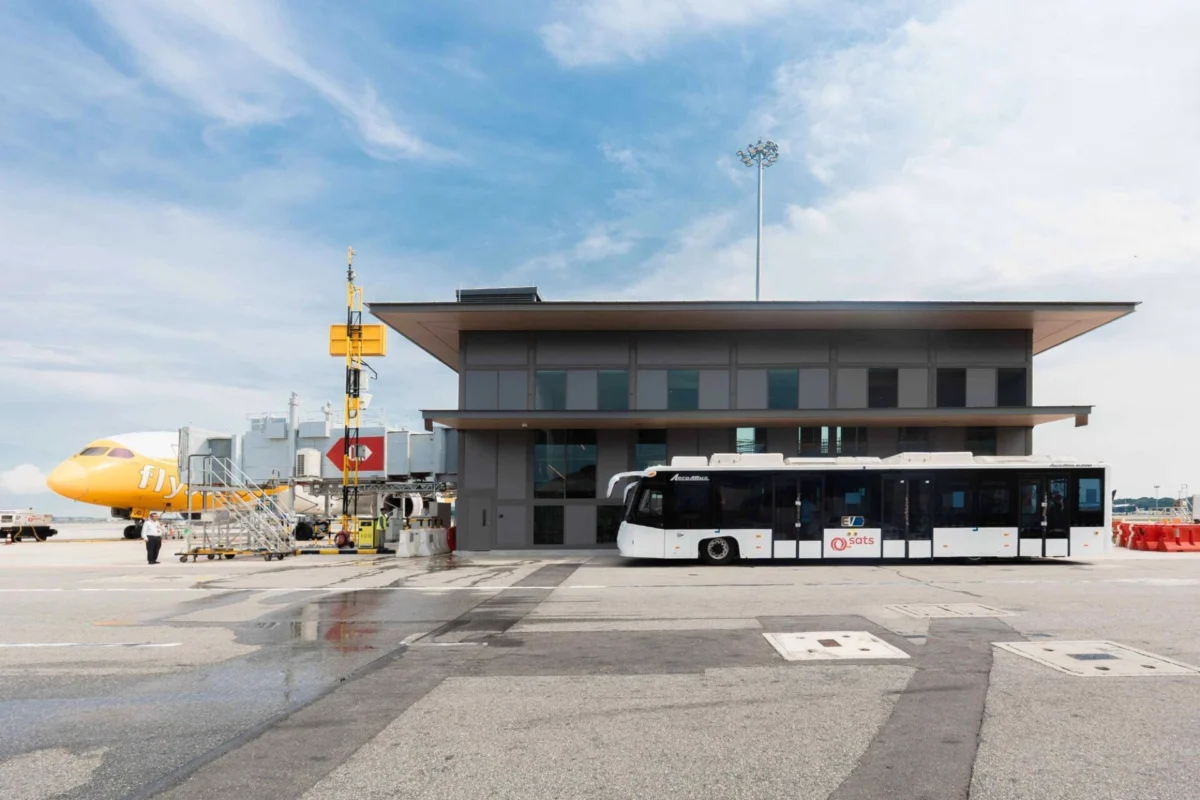 Changi Airport completes first satellite gate for remote ops Airport tarmac with a yellow airplane at the gate a modern gray terminal building and a white bus in front