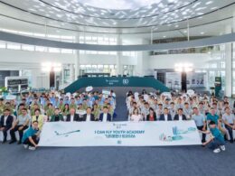 Large crowd of people in a bright atrium pose for a group photo behind a banner that reads I CAN FLY YOUTH ACADEMY with Cathay logos in the background