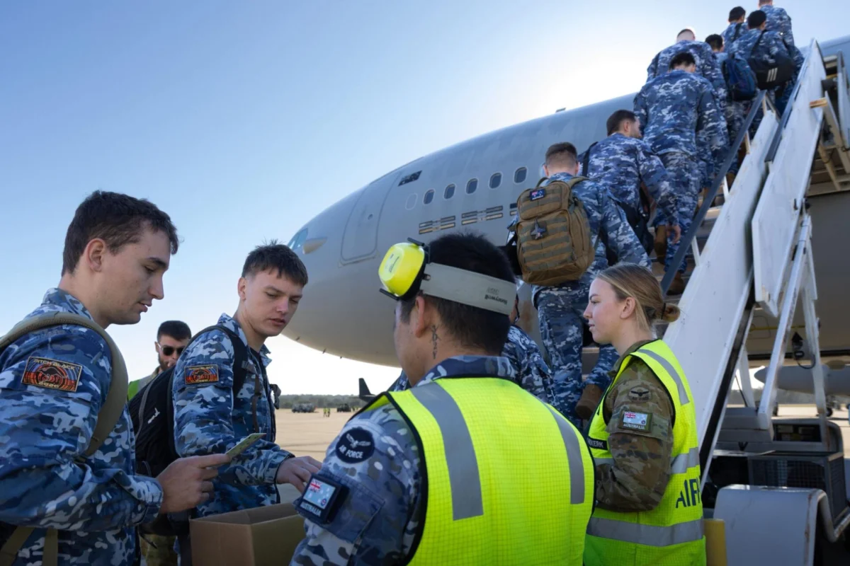 Multinational air power takes over Australias Top End Group of uniformed air force personnel boarding a large military aircraft via mobile stairs guided by a crew member in a high visibility vest