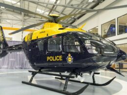 Yellow and navy police helicopter on display inside a hangar with rotor blades extended