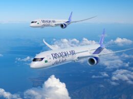 Two Ryanair airplanes in flight over a sea of white clouds against a bright blue sky one closer to the viewer and another farther away in formation