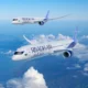Two Ryanair airplanes in flight over a sea of white clouds against a bright blue sky one closer to the viewer and another farther away in formation