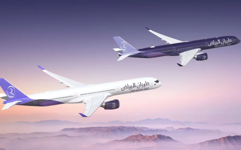 Two Riyadh Air airplanes in purple and white livery fly in formation over a purple pink sunset over a mountainous horizon tails branded with the airline logo