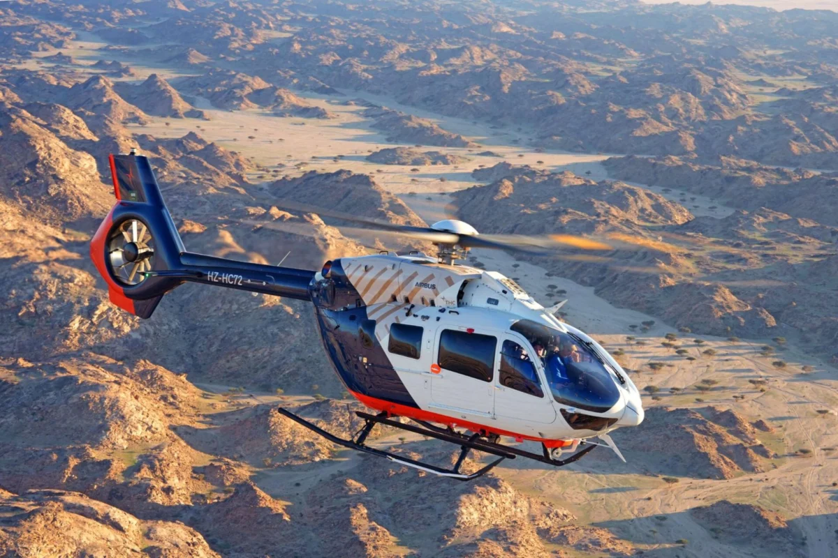 The Helicopter Company orders eight more Airbus H145s Blue and white Airbus helicopter in flight over a rugged desert canyon with rocky hills and dry riverbeds visible below but keep concise