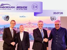 Four men in suits shake hands at Farnborough International Airshow banner reads 2024 July 2026