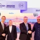 Four men in suits shake hands at Farnborough International Airshow banner reads 2024 July 2026