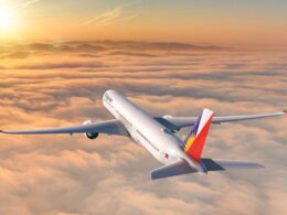 Commercial passenger jet in flight above orange clouds at sunset tail painted with a Philippine flag design