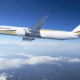 White MSC Air Cargo Boeing 777 freighter flying above clouds against a blue sky yellow and black tail logo visible