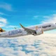 Airbus A320 jet with tiger stripe tail livery flying above a cloudy blue sky