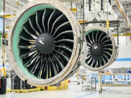 Two large jet engine nacelles suspended in a maintenance hangar showing turbine blades in view