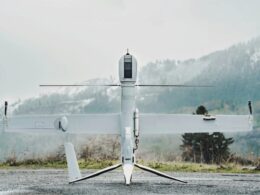 Unmanned aerial vehicle on a ground launch platform white body with long wings against a mountainous backdrop