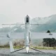 Unmanned aerial vehicle on a ground launch platform white body with long wings against a mountainous backdrop