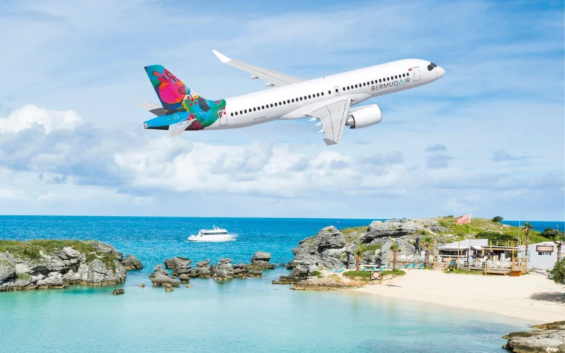 Airliner with a bright colorful tail flying over a tropical beach and rocky shoreline