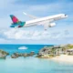 Airliner with a bright colorful tail flying over a tropical beach and rocky shoreline