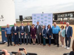 Group of ten professionals posing for a photo at an outdoor press event with a MN SAF Hub backdrop