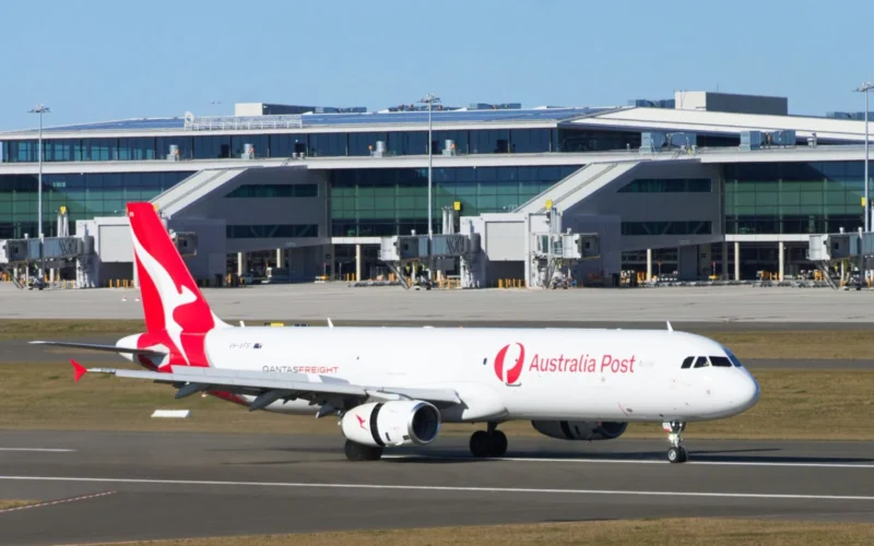 Australia Post aircraft with red tail at a modern airport terminal gate area