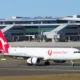 Australia Post aircraft with red tail at a modern airport terminal gate area