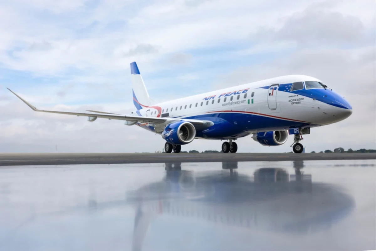Air Peace adds Embraer E175 to fleet for West Africa routes Airplane on a runway with blue nose and tail reflection visible on the wet tarmac under a cloudy sky
