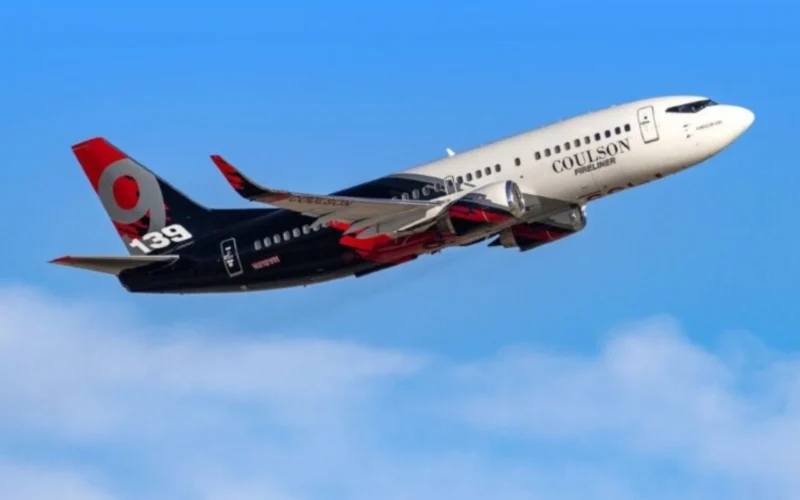 Airplane in flight with white nose and black tail featuring Coulson Fireliner branding against a blue sky number 139 on the tail