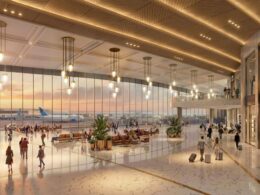 Bright spacious airport terminal with large glass walls warm hanging lights and passengers walking to gates