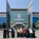 Group of diverse people posing for a photo in front of a modern Emirates building with glass facade and flags
