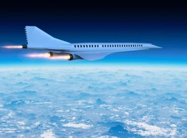 White jet airliner flying above a sea of clouds against a deep blue sky, engines blazing.