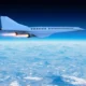 White jet airliner flying above a sea of clouds against a deep blue sky engines blazing