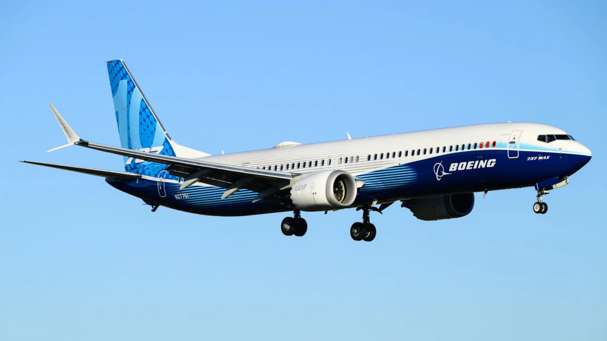 aircraft 737 max Blue and white Boeing 737 MAX in flight with landing gear extended against a clear blue sky