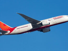Air India aircraft in white and red livery flying against a clear blue sky angled upward