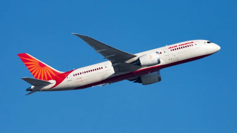 Air India aircraft in white and red livery flying against a clear blue sky angled upward