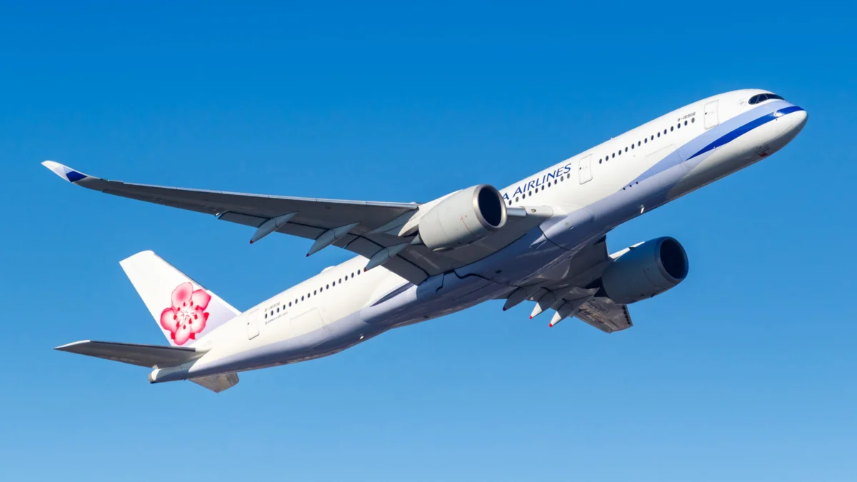 airline china airlines White passenger jet climbs in a clear blue sky with a pink flower logo on the tailfin
