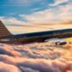 Commercial airplane with a circular pattern livery flies above orange pink clouds at sunset BEOND branding visible on the fuselage