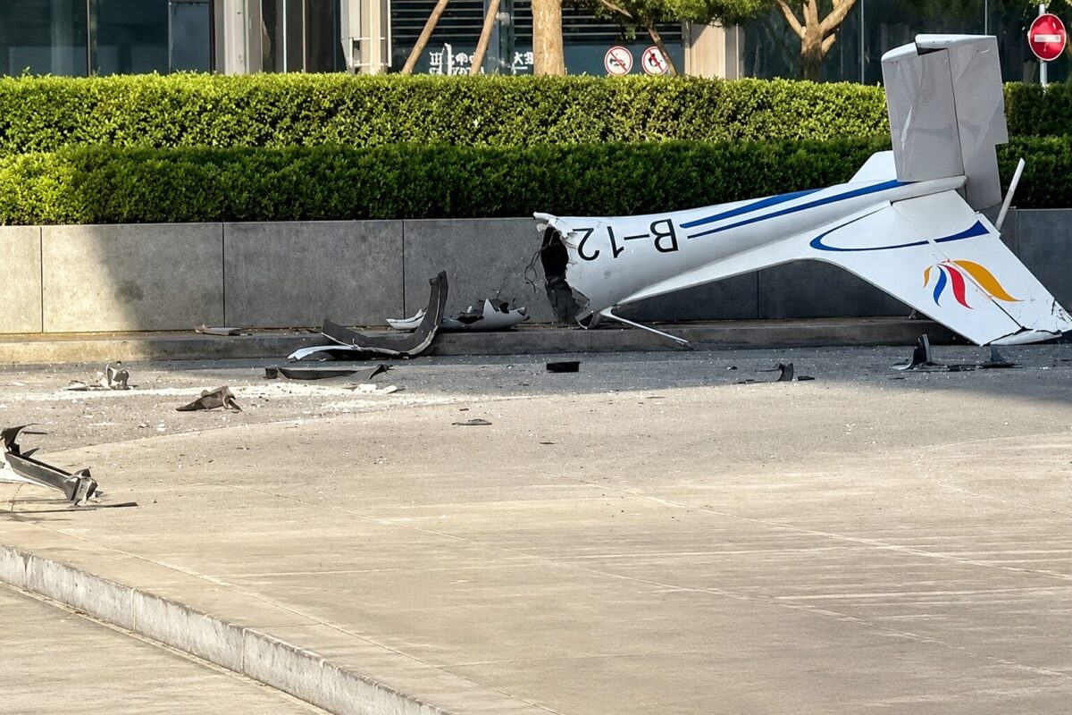 beijingcfrash Small white airplane wrecked on a road with blue stripes tail damaged and scattered debris nearby