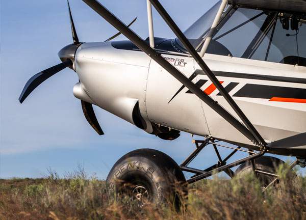 carbon cub ult drop down 2dbe13df643ad67bb223aee9d030fe22fa2bbff81a6e43bb68176946d1010781 Light sport airplane on grassy field close up of nose and propeller with visible landing gear and struts under a clear sky