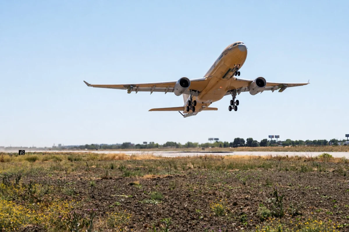 cnd32 Wide angle shot of a passenger jet taking off from a runway under a bright blue sky landing gear down with dry grassy foreground below