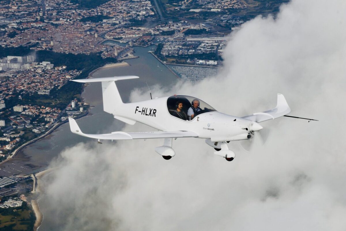 f0d1c85cd494a6928530aec484451933936d23f64a615ffe144b45d854996f0e 2048x1365 Twoperson white light aircraft in flight over a coastal city with a marina below clouds around it