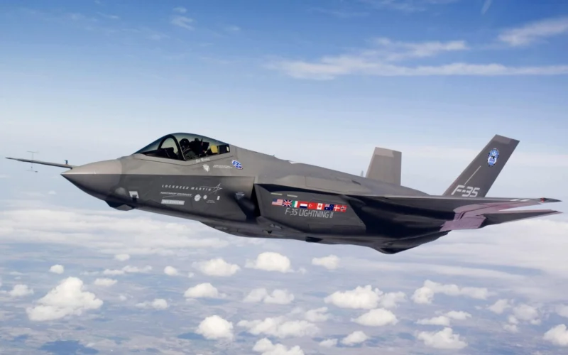 Grey F 35 Lightning II fighter jet in flight above a sea of white clouds nose to the left and cockpit canopy visible