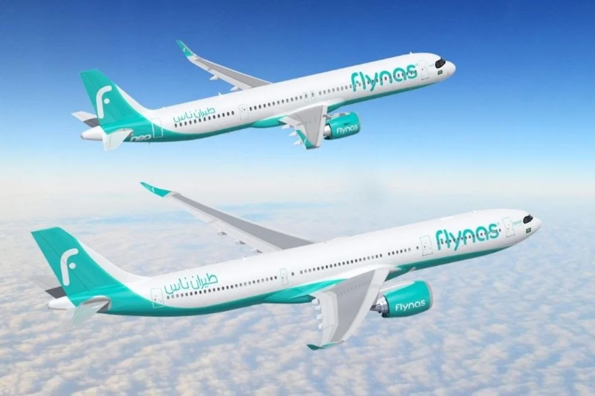 flynas airbus Two Flynas airplanes in teal livery flying above cloudy sky