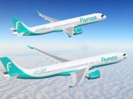 Two Flynas airplanes in teal livery flying above cloudy sky