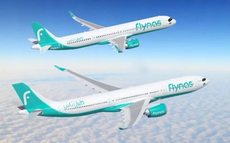 Two Flynas airplanes in teal livery flying above cloudy sky