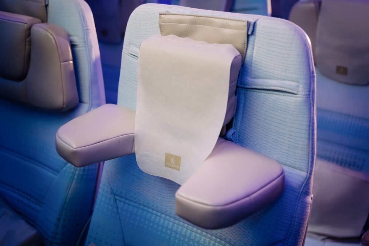 image Business class airplane seats in blue fabric with a white napkin draped over the headrest showing an Emirates logo at the bottom edge