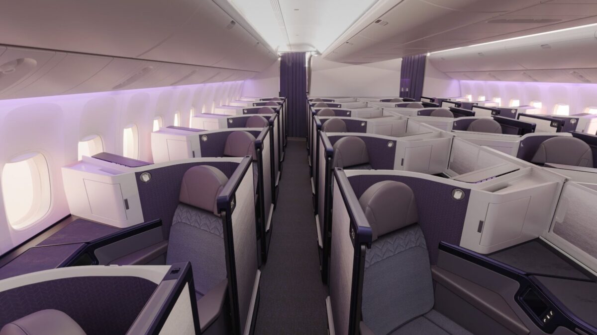 image Wide angle view of a modern airplane business class cabin with lie flat seats in purple lit pods along a central aisle