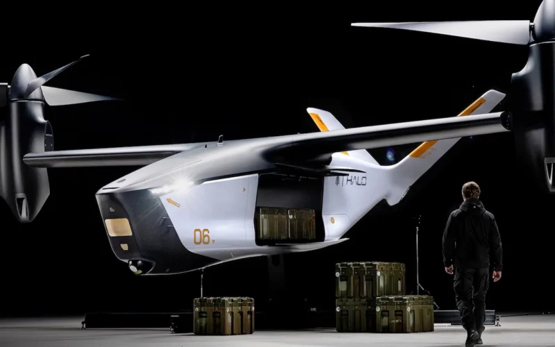 White futuristic twin rotor aircraft in a dim hangar with cargo crates beneath and a person in dark gear nearby