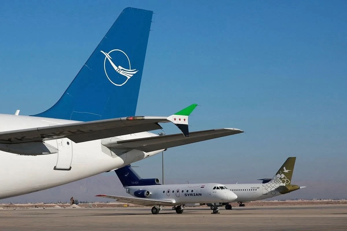 01K6HZ0V1BMEFMBCM3752778SG Airplanes parked on a sunny tarmac with a large blue tail fin in the foreground and a Syrian Airlines jet in the midground behind it