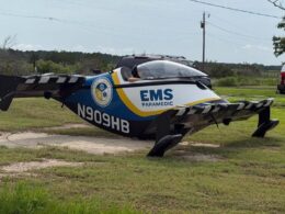 Air ambulance helicopter on the ground with EMS Paramedic branding and blue yellow livery registration N909HB in a grassy field